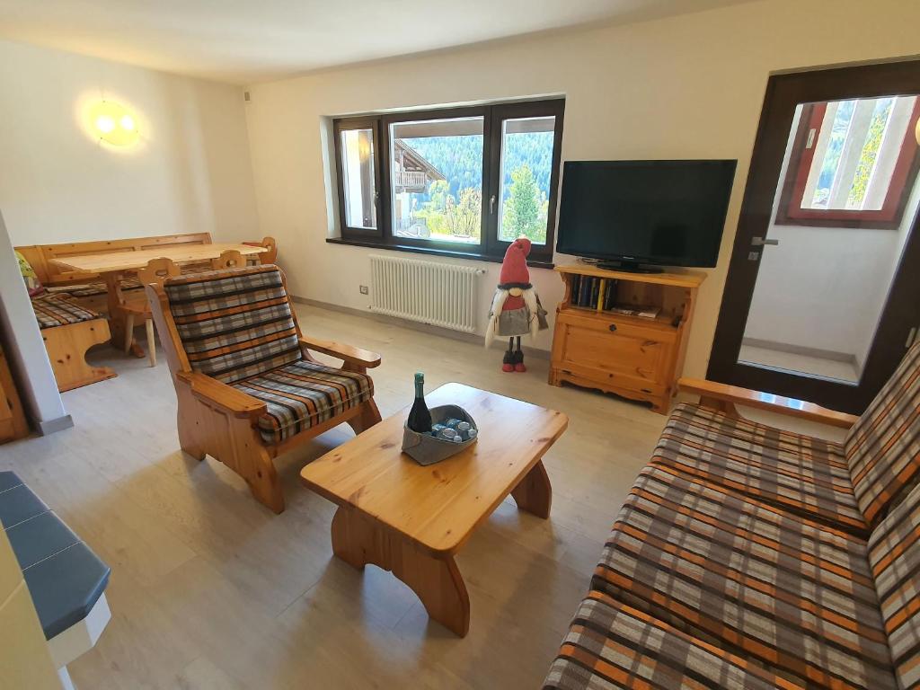 sala de estar con mesa de centro y TV en Il Rifugio dello Gnomo - Alpine Stay Apartments, en Panchia