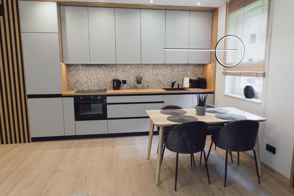 a kitchen with white cabinets and a table and chairs at Nice River Apartment in Ostróda