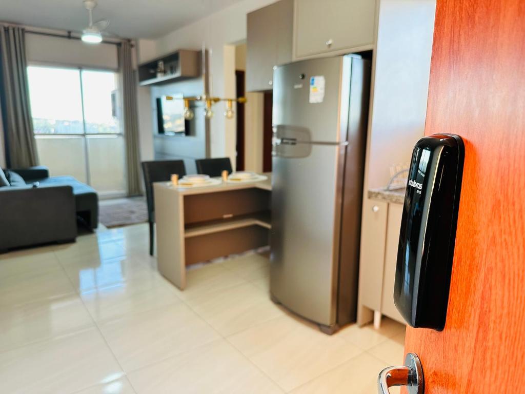 an office with a refrigerator and a living room at Apartamento Cuiabá - Luxxor Flat in Cuiabá