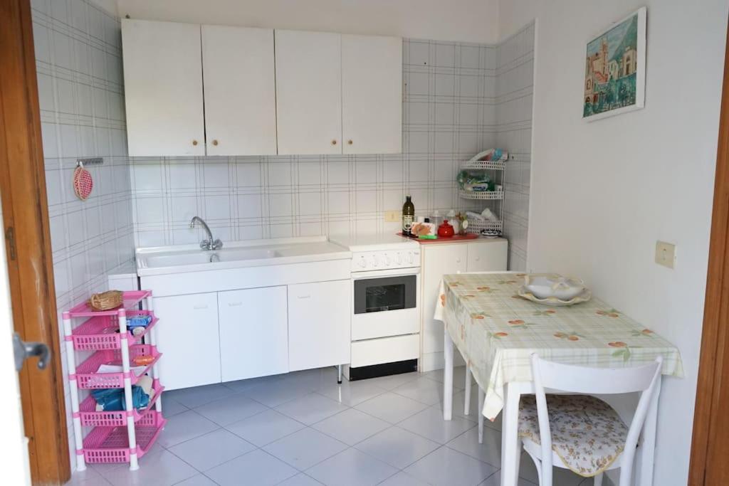 una cucina con armadi bianchi, tavolo e lavandino di FM Apartaments Forio a Ischia