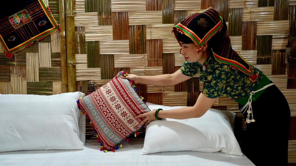a woman standing on a bed holding a pillow at Homestay Minh Ngọc in Ban Hin Lom