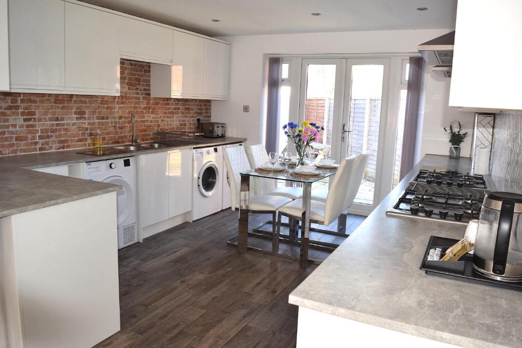 a kitchen with white cabinets and a table with chairs at Like Your Own Private Hotel in Luton