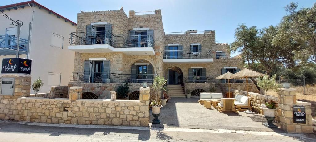 a large stone house with a stone wall at Selinopetra Rooms in Elafonisos