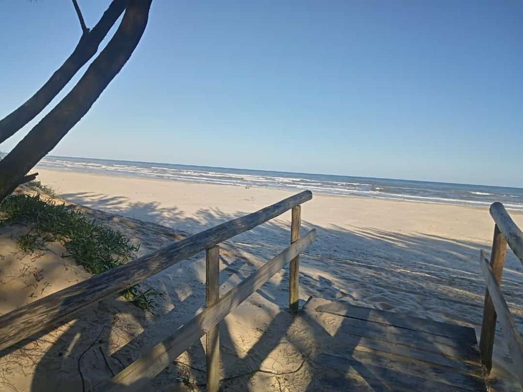 una valla de madera en la playa cerca del océano en Apartamento a Beira Mar, en Jaguaruna