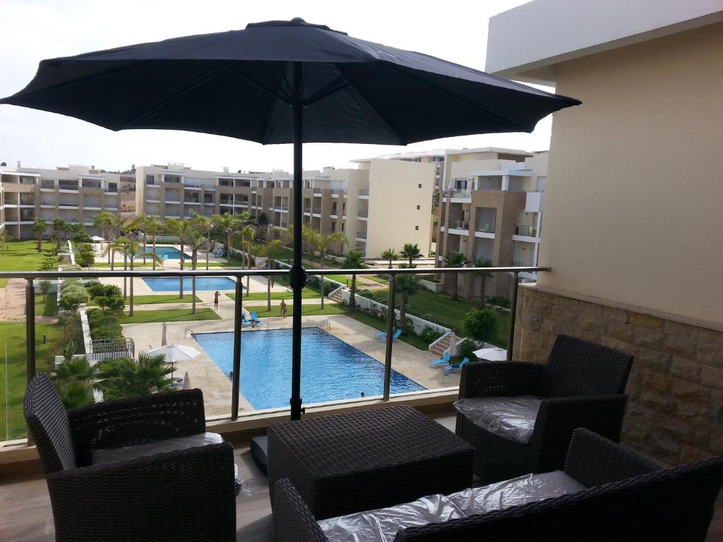une terrasse avec un parasol, des chaises et une piscine dans l'établissement LE GRANd BLEU - ONLY FAMILIES, à Sidi Bouqnadel