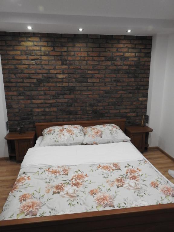 uma cama num quarto com uma parede de tijolos em Mieszkanie na Flo em Florynka