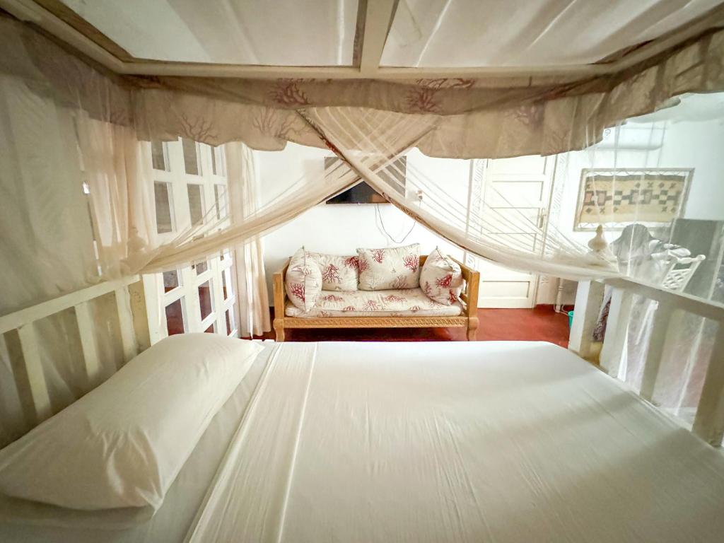 a bedroom with a bed and a chair and a window at Kaleb's Beachfront Villa in Malindi