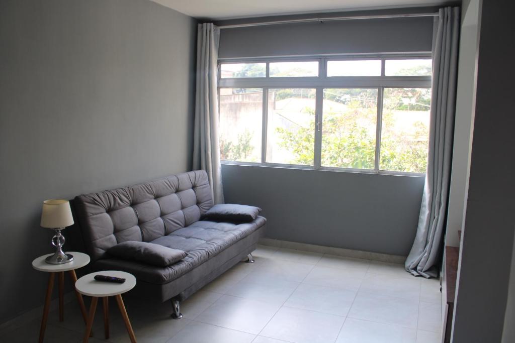 sala de estar con sofá y ventana grande en Apartamento confortável rodeado de verde e serviços en São Paulo