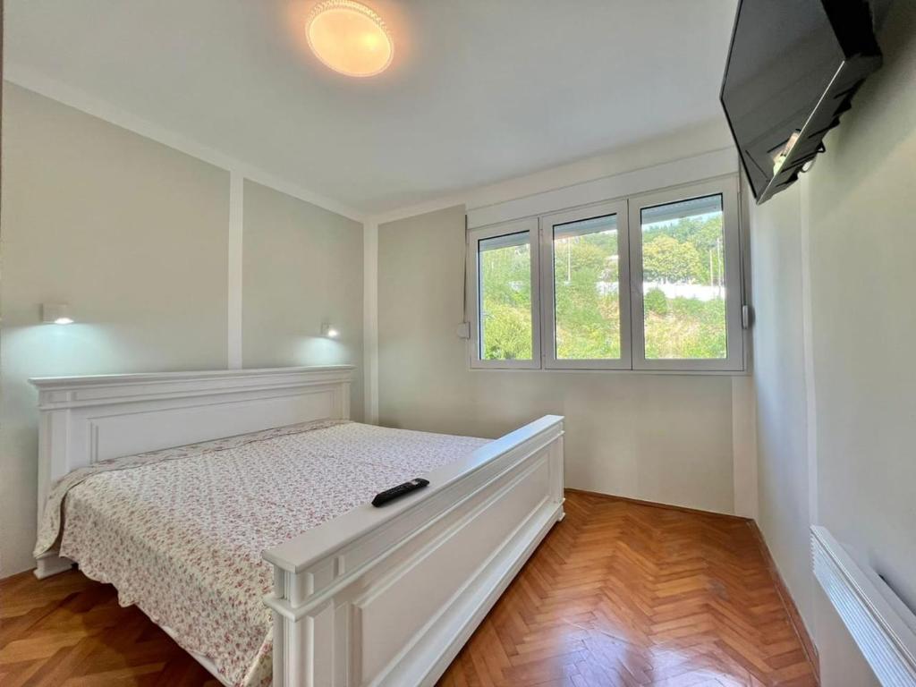 um quarto branco com uma cama e 2 janelas em Melanie- City Centre Apartment em Herceg Novi