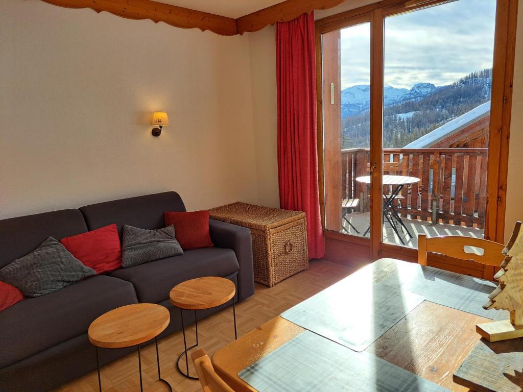 sala de estar con sofá y ventana grande en - Appartement avec balcon - 2 personnes en Puy-Saint-Vincent