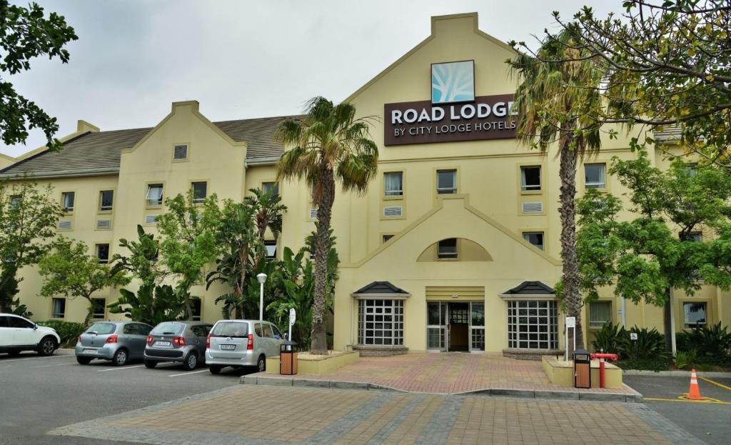 un grand bâtiment jaune avec des voitures garées devant lui dans l'établissement Road lodge Hotel Cape Town International Airport -Booked Easy, au Cap