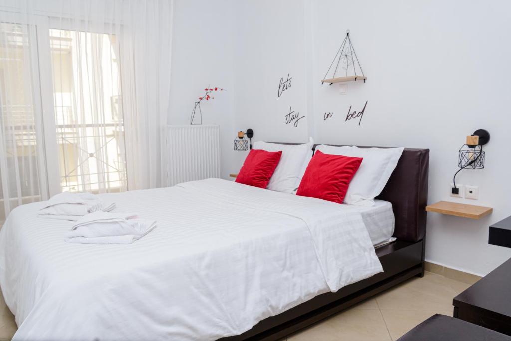 1 dormitorio con 1 cama blanca grande con almohadas rojas en WhiteHome Apartment en Xanthi