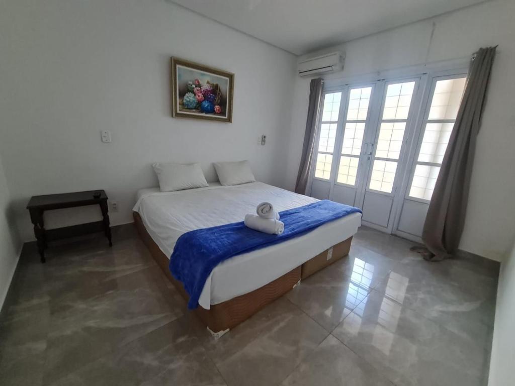 een slaapkamer met een bed met een blauwe deken bij Wafeh Fleming Suítes Pampulha in Belo Horizonte