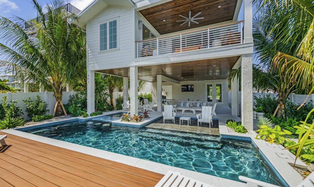 una casa con piscina frente a una casa en From Dusk 'Til Dune, Gorgeous 5 beds, 5,5 Baths Home on the Canal and steps away from the beach! en Anna Maria