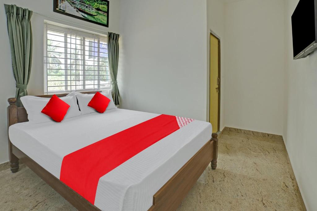 um quarto com uma cama com almofadas vermelhas e uma janela em Flagship M & M Hospitality em Devanhalli