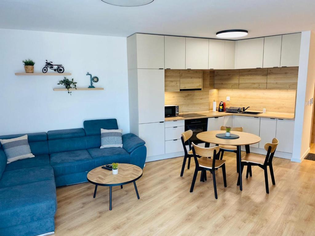 een woonkamer met een blauwe bank en 2 tafels bij Modern appartment in Banská Bystrica