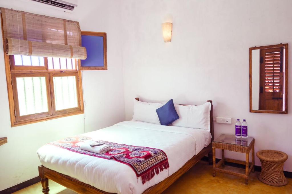 FRENCH RIVERA Heritage Boutique Villa في بونديتْشيري: غرفة نوم بسرير وطاولة صغيرة