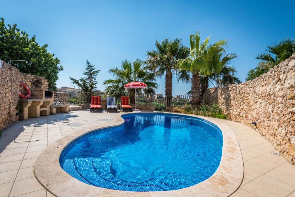 a swimming pool in a yard with a stone wall at 3 Bedroom Holiday Home with Private Pool and Views in Nadur