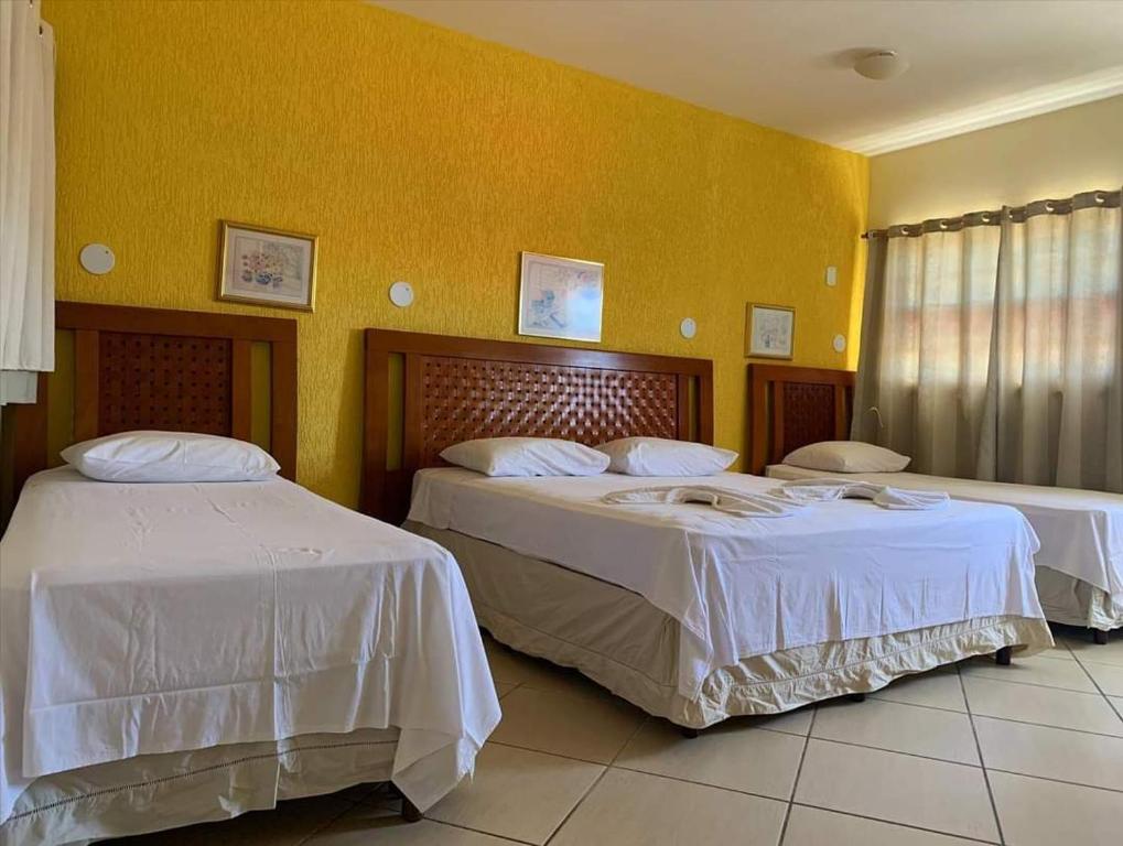 2 camas en una habitación con paredes amarillas en Pousada Enseada da Vila, en Cabo Frío