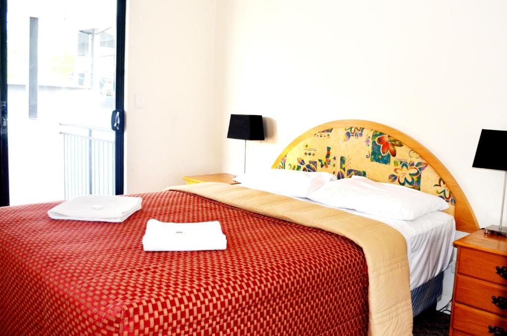 sypialnia z dużym łóżkiem i czerwonym kocem w obiekcie Spring Hill Mews Apartments w mieście Brisbane