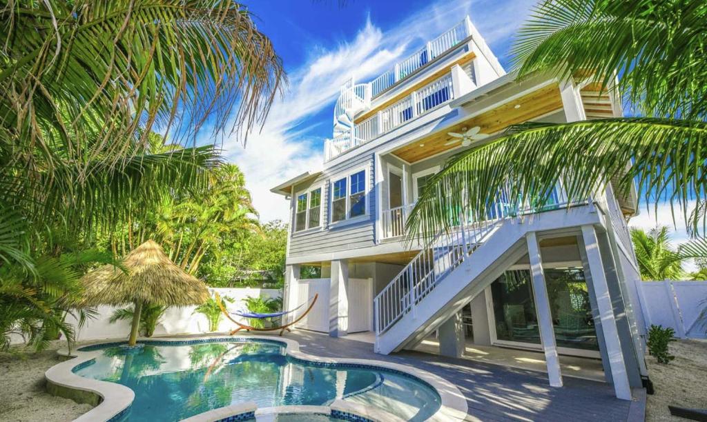 a house with a swimming pool in front of it at Surfer's Dream, 4 King beds, 4 trundle beds, 6 full baths, pet-friendly with a rooftop deck! in Holmes Beach