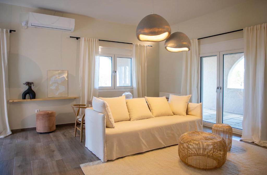 a living room with a white couch and some windows at Oinopia Apartments in Aegina Town