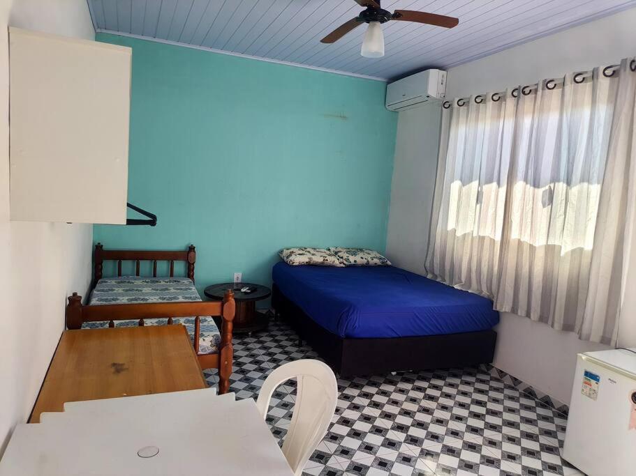 a small room with a bed and a table at Suites do Rafa Ubatuba in Ubatuba