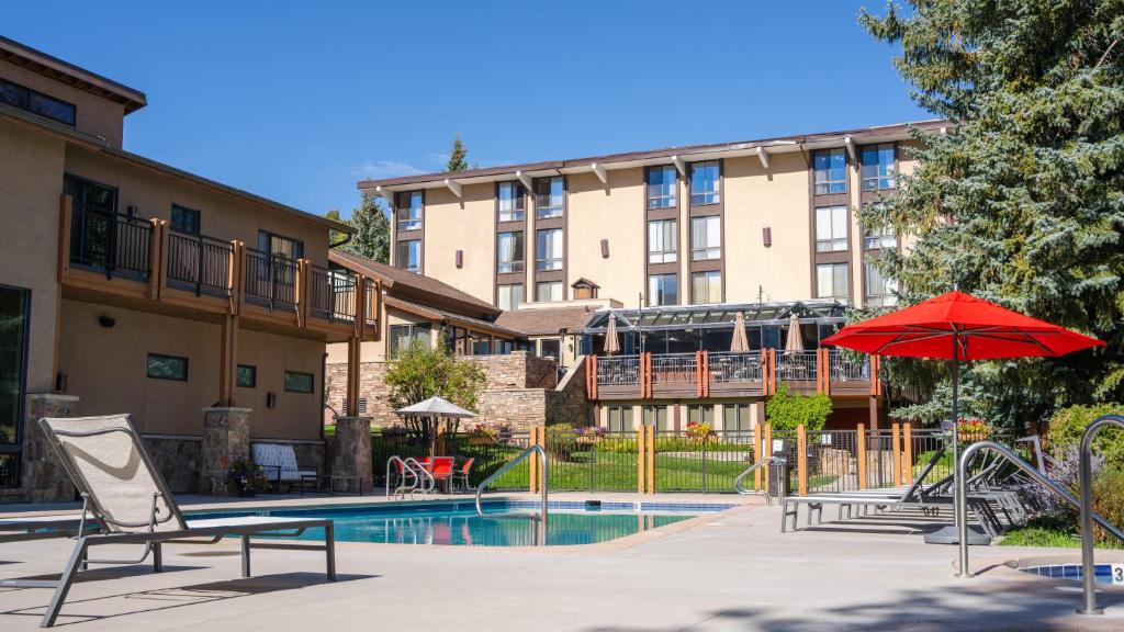 a hotel with a pool with chairs and an umbrella at Stonebridge Inn in Snowmass Village