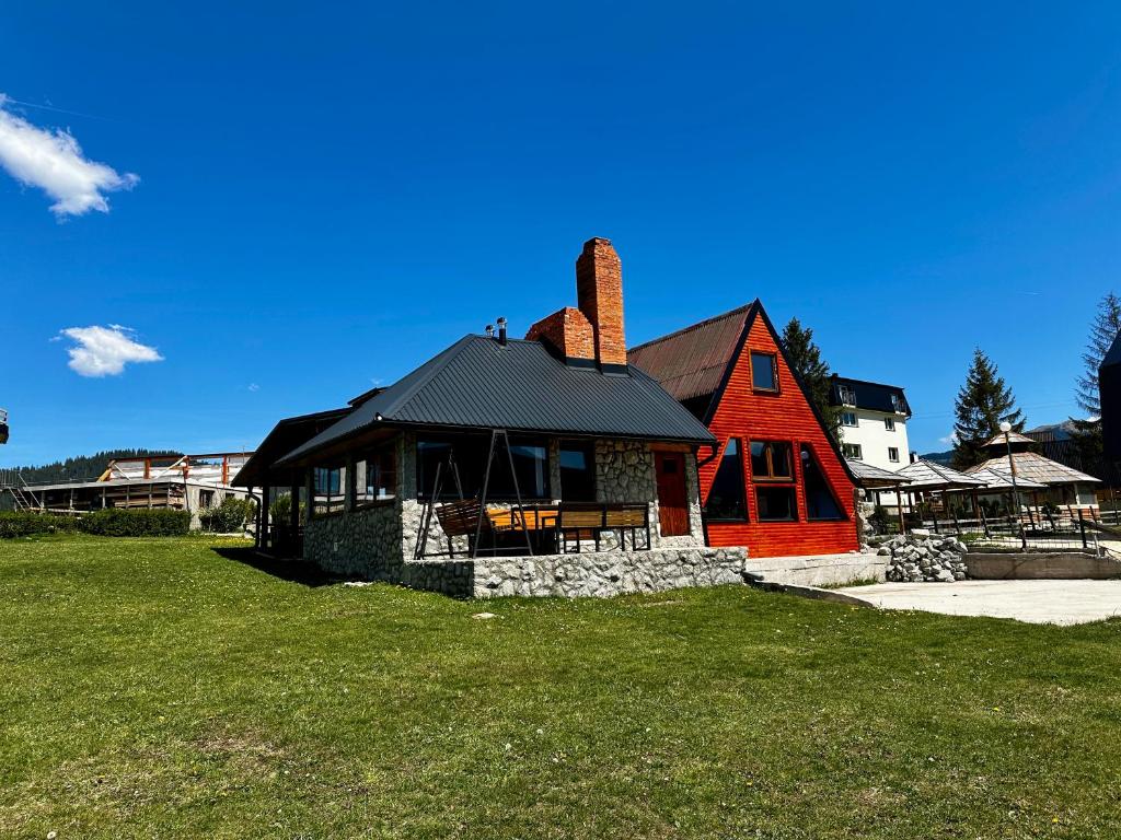 a red house with a black roof on a green field at Holiday home Kraljica in Vlasic