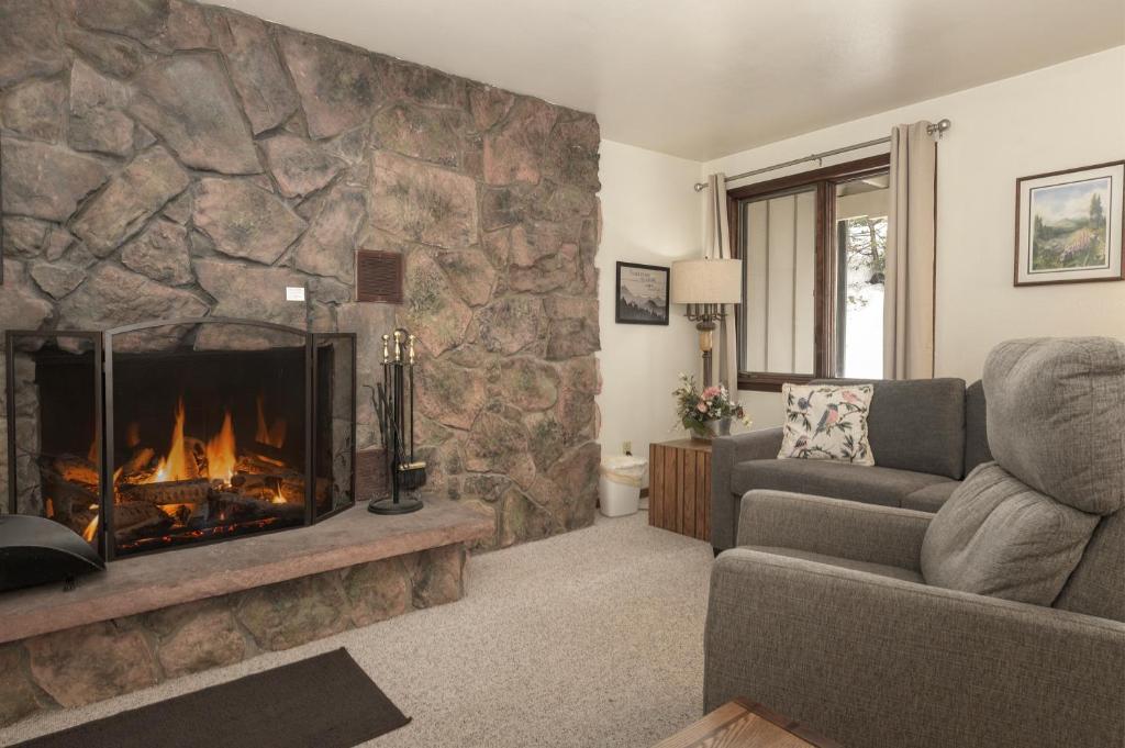 a living room with a large stone fireplace at Hideaway Village Alpine 4 in Winter Park