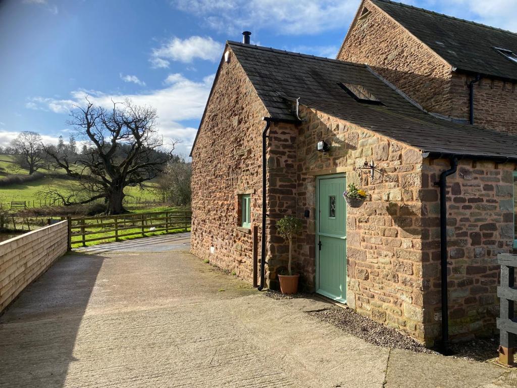 an old brick building with a green door at Oaklands Cottage on a rural farm in Dingestow