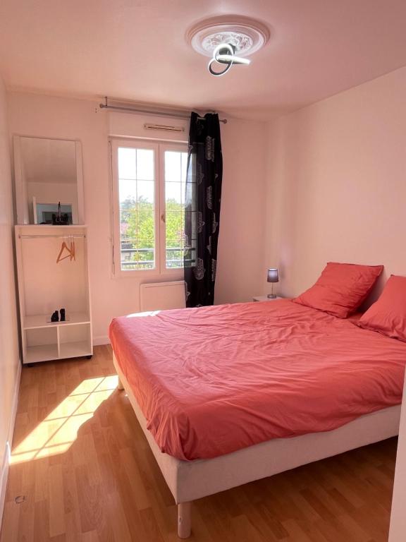 Schlafzimmer mit einem Bett mit roter Bettwäsche und einem Fenster in der Unterkunft Maison de Caractère à Ballainvilliers in Ballainvilliers