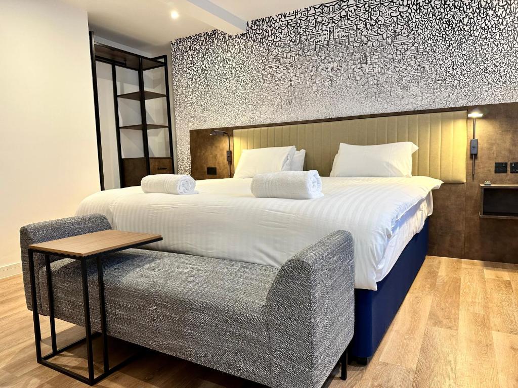 a bedroom with a large bed and a chair at Rhode Lane - Serviced Apartments Bridgwater in Bridgwater
