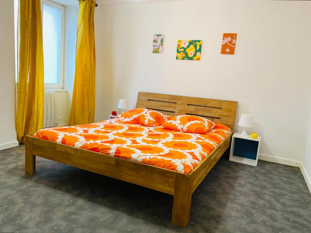 um quarto com uma cama com lençóis e almofadas laranja em Black em Ensisheim