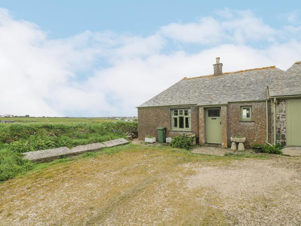 a brick house with a green door and a field at Parc An Castle Cottage in Lizard