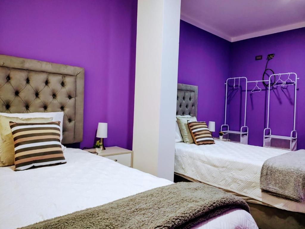 2 łóżka w pokoju z fioletowymi ścianami w obiekcie SHUMAQ YUNGAY - Depas w mieście Yungay