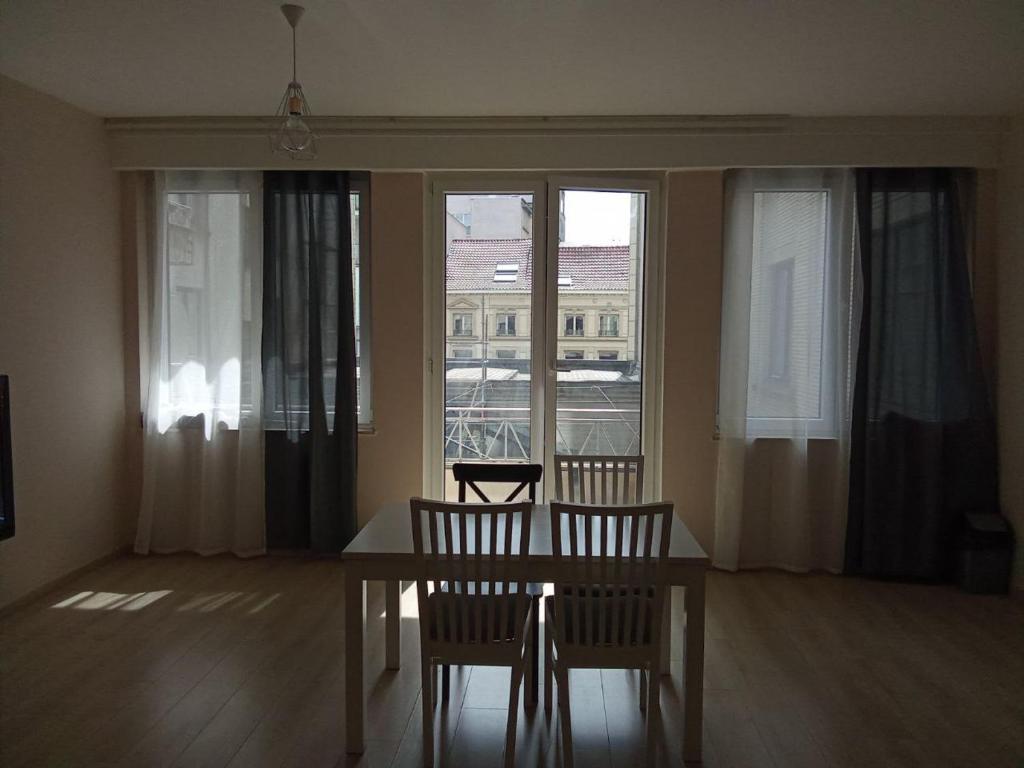 comedor con mesa, sillas y ventanas en Viola Apartments Brussel Stay en Bruselas