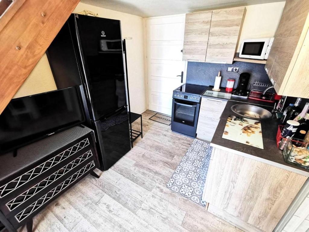 une cuisine avec un réfrigérateur noir et une cuisinière dans l'établissement Résidence Cote D'oc - Appartement deux pièces mezzanine - 4 couchages PORT LEUCATE. 2CO_35B MAE-7041, à Leucate