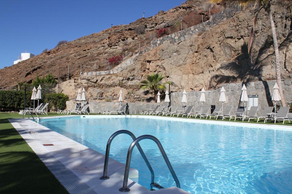 - une piscine avec des chaises et une montagne dans l'établissement APARTAMENTOS CANAIMA, à Puerto Rico