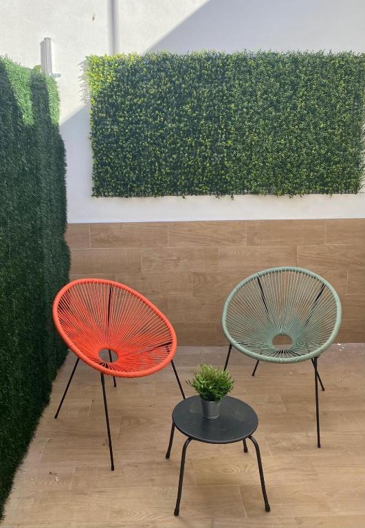 two chairs and a table in front of a hedge at El Parador del César Boutique, Aparcamiento Gratis in Mérida