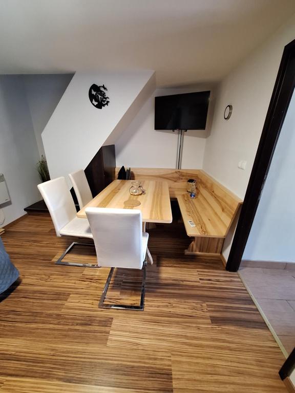 sala de estar con mesa de madera y sillas blancas en Hiška Ela 109, en Mostec