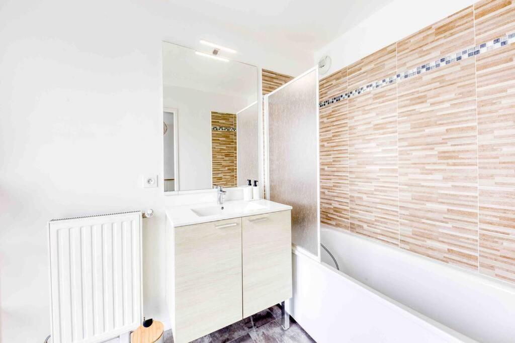 a bathroom with a sink and a tub and a mirror at Duplex cosy - Proche Aéroport Paris CDG in Montfermeil