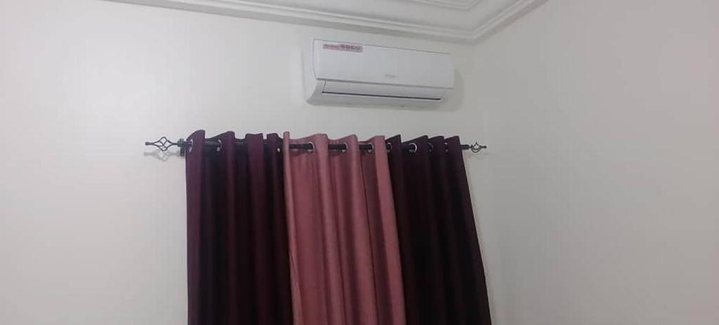 une pièce avec des rideaux et un climatiseur sur un mur dans l'établissement AMDI Appartement, à Dakar