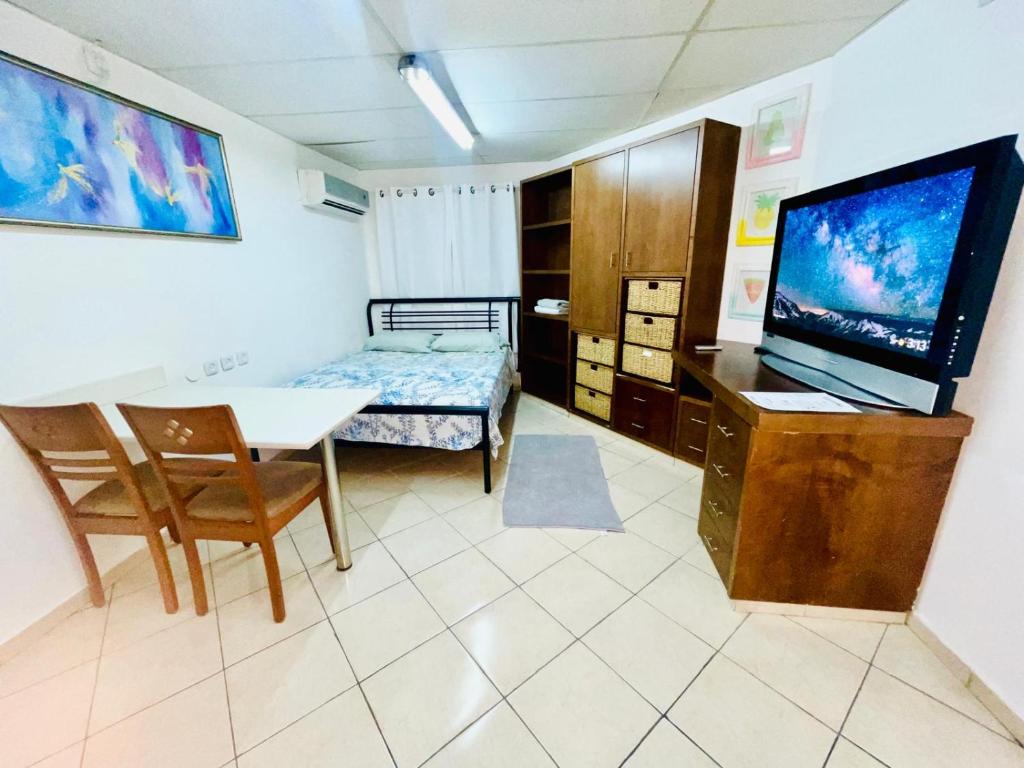 a room with a table and a bed and a television at Eilat Beach House in Eilat