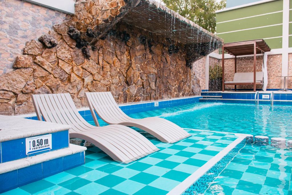 Duas espreguiçadeiras ao lado de uma piscina em Hotel Punta Arena Spa Boutique em Arauca