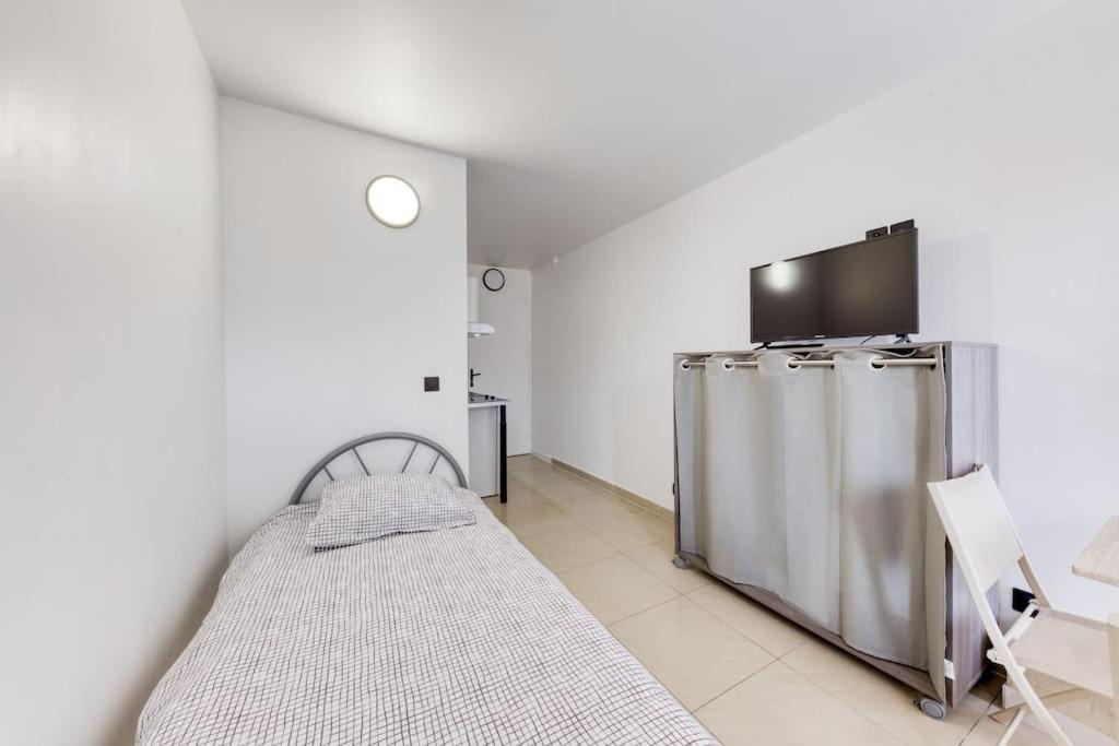une chambre avec un lit et une télévision dans l'établissement Studio douillet, à Sarcelles
