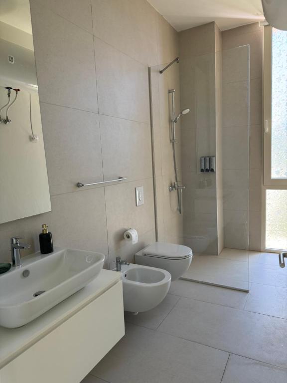 a white bathroom with a sink and a toilet at Green Gem Villas Palase 82A in Green Coast in Dhërmi