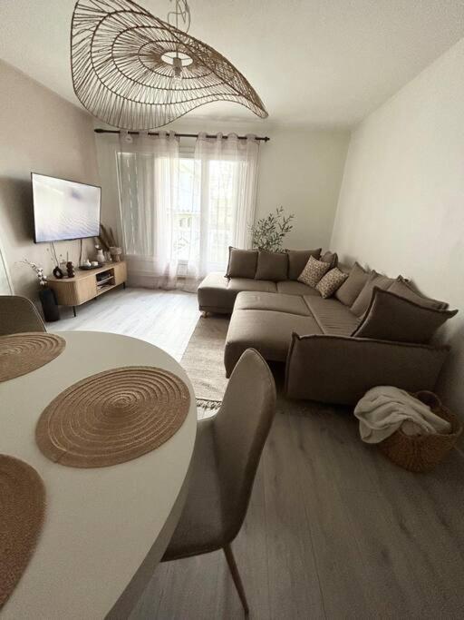 ein Wohnzimmer mit einem Sofa und einem Tisch in der Unterkunft Appartement spacieux 6 personnes in Magny-les-Hameaux