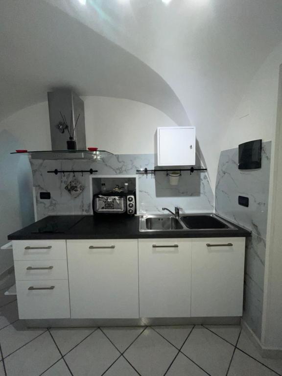 eine Küche mit einer Spüle und einer Mikrowelle in der Unterkunft casa Alkamà in Castellammare di Stabia