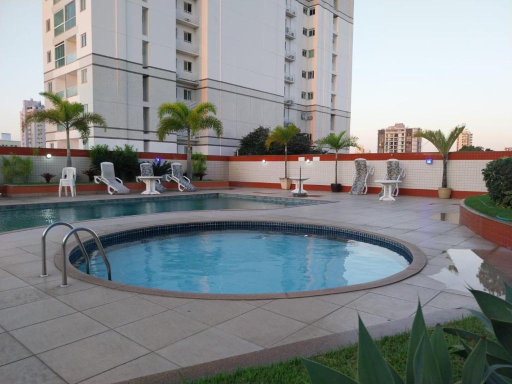 uma piscina num pátio com cadeiras e um edifício em Flat e Suíte no Via Park - NF e Wi-FI em Campos dos Goytacazes